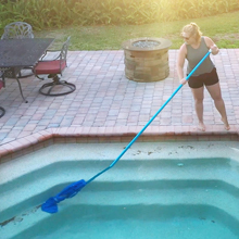 une femme nettoyant une piscine avec un balai.