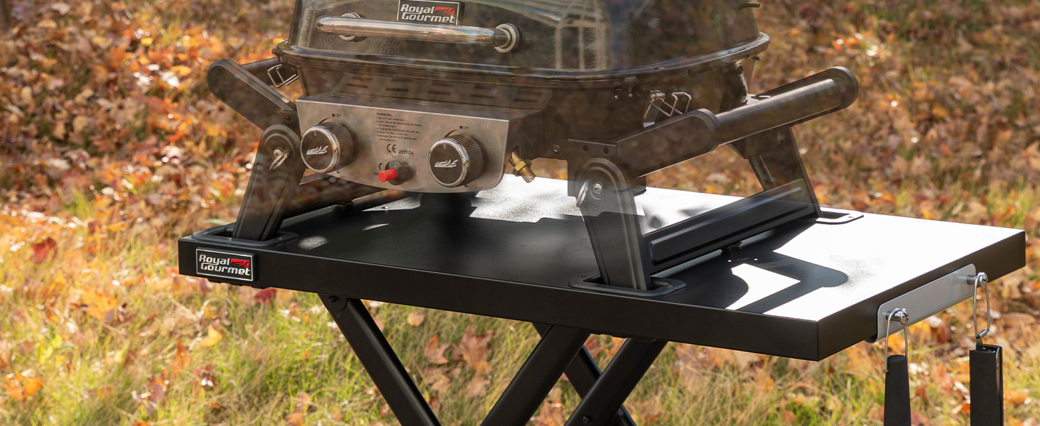 avec grill plat. Comprend des tables d'appoint pliantes, des boutons de commande et un cadre métallique robuste. Installé dans un décor automnal extérieur.