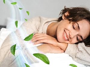 Literie blanche avec des feuilles de menthe verte éparpillées créant une atmosphère d'aromathérapie relaxante