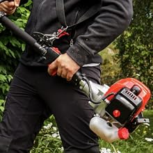 Gros plan des mains qui actionnent un coupe-herbe à essence rouge sur fond de feuillage vert