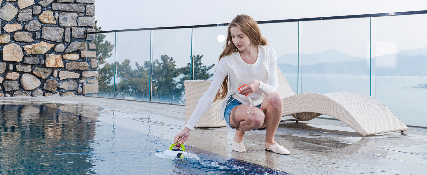 Le texte se lit comme suit : « Image 2 ». Personne nettoyant ou entretenant le bord d'une piscine à débordement dotée d'un mur en pierre et d'une balustrade en verre, outil de brosse de piscine en cours d'utilisation.